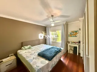 Quarto com cama e janela, com piso de madeira.