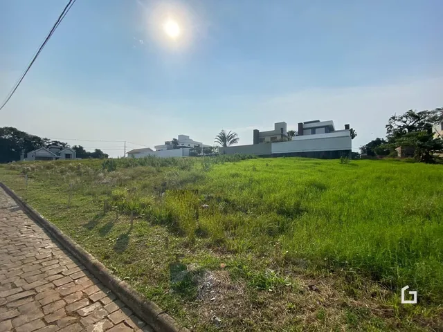 Vista externa de uma propriedade com terreno gramado e uma estrada no primeiro plano.