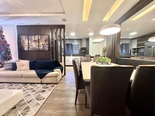 Sala de estar e jantar com sofá e mesa de jantar em um apartamento.