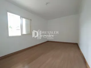 Interior de uma sala com piso de madeira e janela.