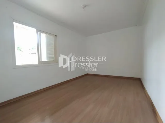 Interior de uma sala com piso de madeira e janela.