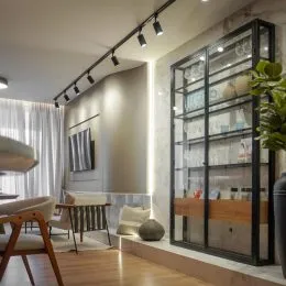 Sala de estar com estante de vidro preta e iluminação de trilho.