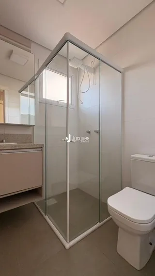 Foto de um banheiro com box de vidro e vaso sanitário em um imóvel.