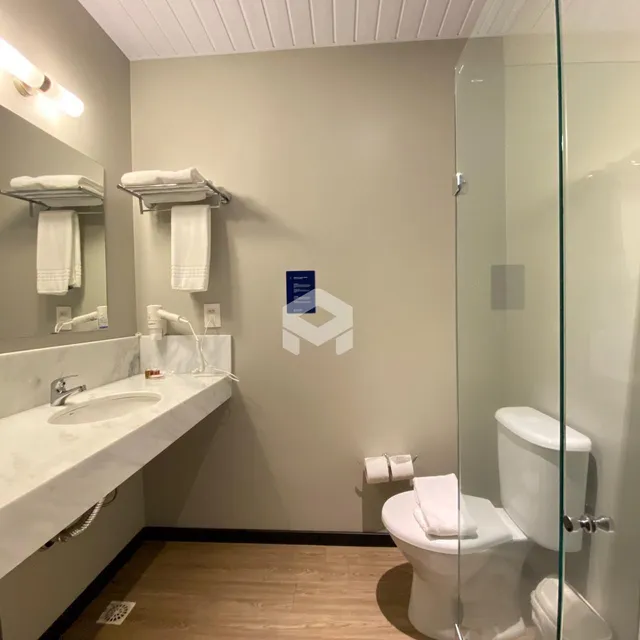Banheiro com bancada de mármore e box de vidro.