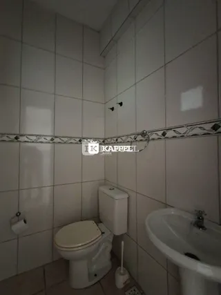 Foto de um banheiro com azulejos brancos e vaso sanitário.