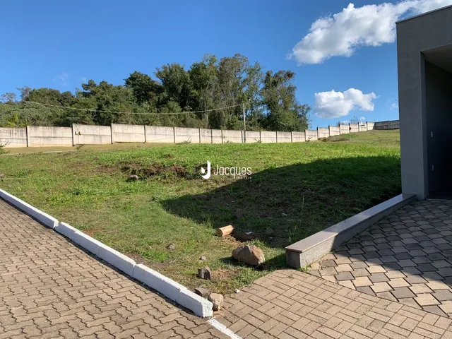 Vista externa de um terreno gramado com cerca de madeira e calçada de tijolos.