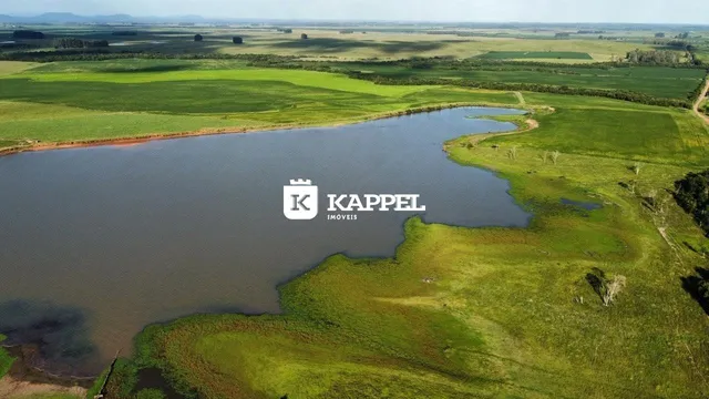 Vista aérea de um corpo d'água cercado por campos verdes e vegetação.