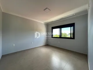 Ambiente interno de uma sala ampla com paredes brancas e piso claro.