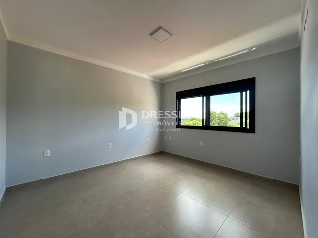 Ambiente interno de uma sala ampla com paredes brancas e piso claro.