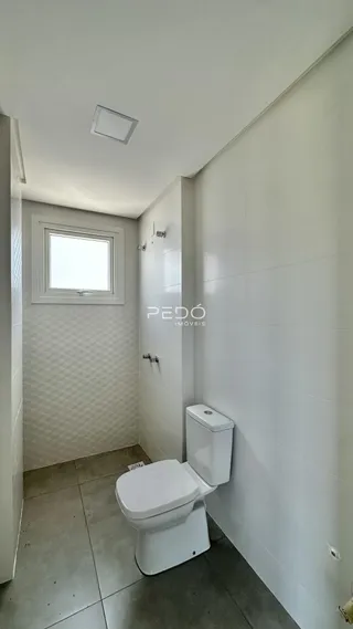 Banheiro com revestimento cerâmico e louças brancas.