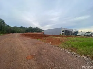 Vista externa de um edifício comercial em uma área de terreno aberto.