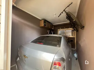 Hall de entrada com um carro estacionado e prateleiras de madeira na parede.