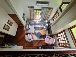 Sala de estar com pé direito alto e piso de madeira escura.