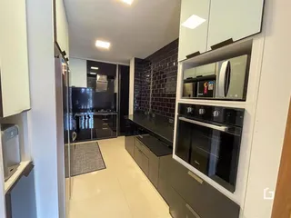 Vista interna de uma cozinha moderna com armários escuros e piso claro.