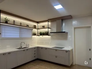 Cozinha moderna com armários brancos e bancadas claras.