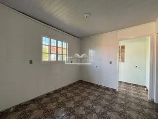 Interior de um cômodo com piso de cerâmica escura e paredes brancas.