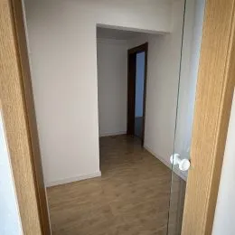 Corredor interno com paredes brancas e piso de madeira.