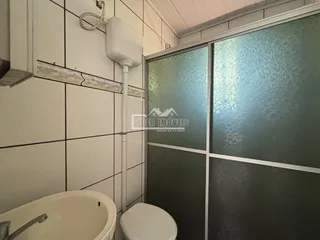Foto de um banheiro com azulejos brancos e divisória de vidro.