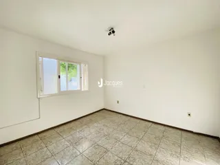 Foto de uma sala de estar vazia com piso de cerâmica clara e paredes brancas.