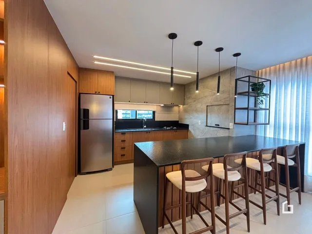 Foto de uma cozinha moderna com ilha e bancadas escuras.