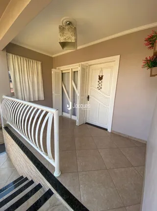 Hall de entrada com piso de cerâmica e corrimão branco.