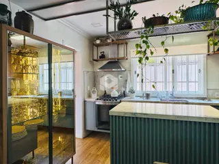 Vista da cozinha com grandes janelas e decoração verde.