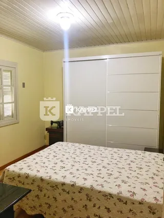 Quarto com cama coberta e um grande armário branco.