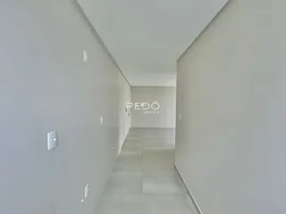 Corredor interno de um imóvel com paredes brancas e piso claro.