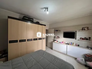 Quarto com armário em madeira e televisão na parede.