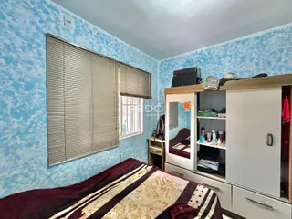 Quarto com cama e janela com persianas na decoração de uma residência.