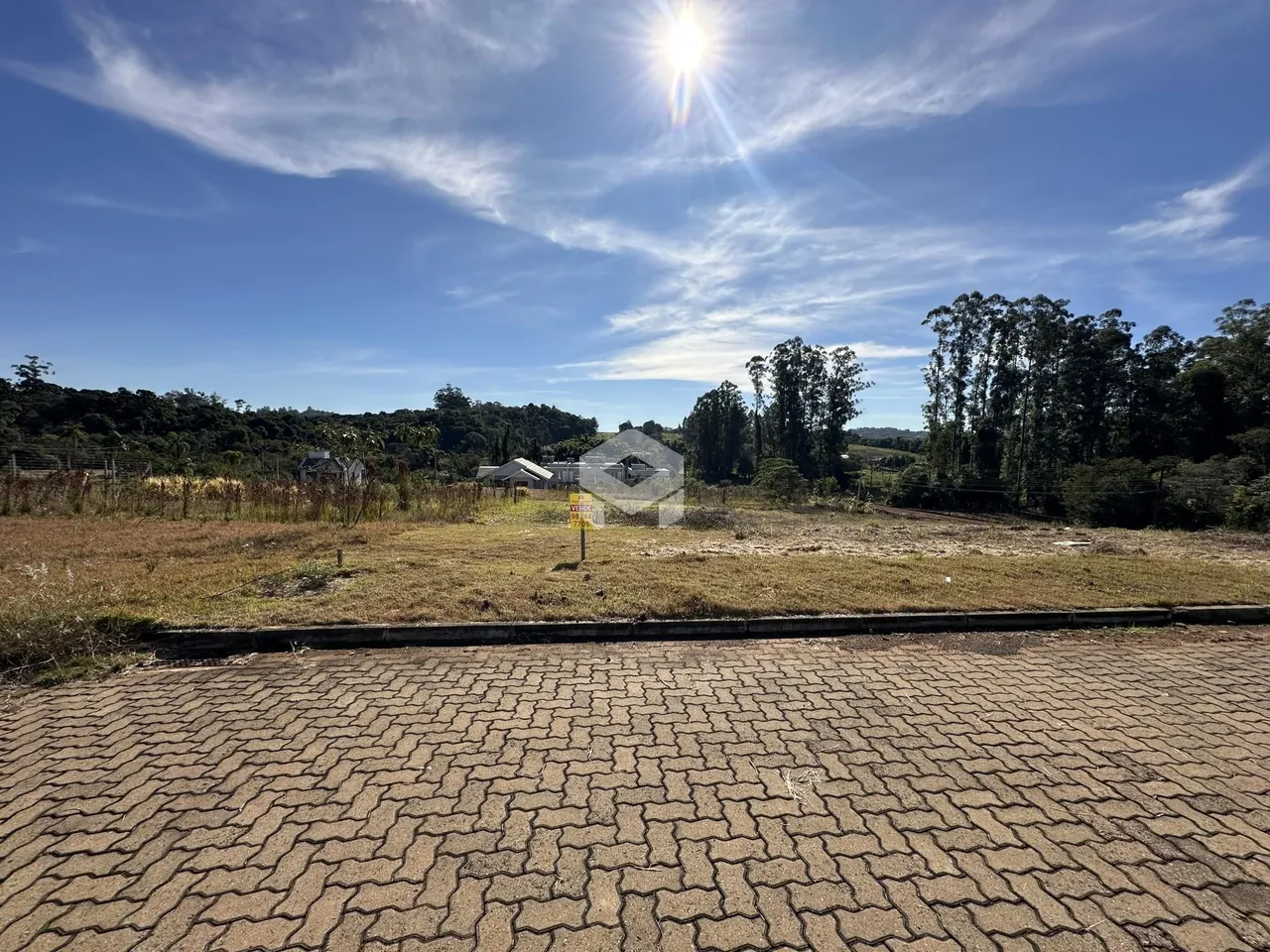 Vista da propriedade com vegetação e campo aberto.