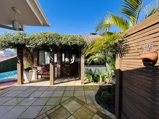 Vista externa de um pátio com vegetação tropical e muro de madeira.
