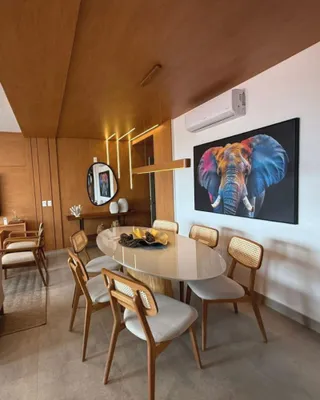 Sala de jantar com mesa redonda e cadeiras de vime em um ambiente bem iluminado.