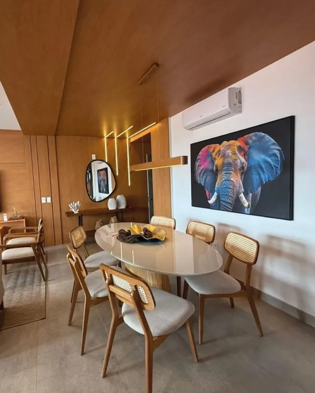 Sala de jantar com mesa redonda e cadeiras de vime em um ambiente bem iluminado.