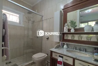 Banheiro com box de vidro e bancada de mármore.
