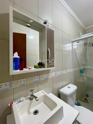 Um banheiro com azulejos brancos e louças sanitárias brancas.