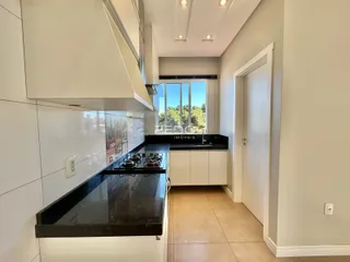 Cozinha moderna com armários brancos e bancada escura.