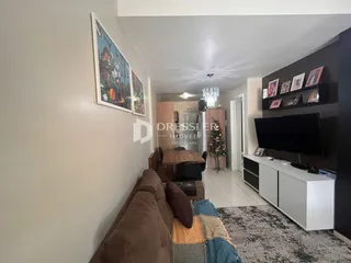 Uma sala de estar com sofá e decoração de parede em um imóvel no Brasil.