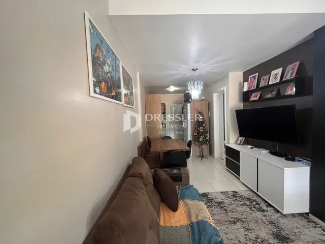 Uma sala de estar com sofá e decoração de parede em um imóvel no Brasil.
