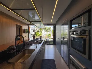 Vista da cozinha moderna com ilha e portas de vidro que dão acesso ao exterior.
