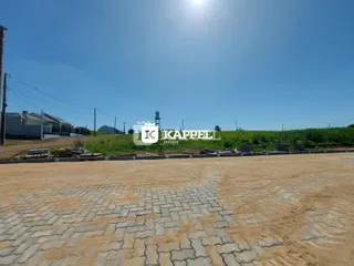 Vista externa de um terreno em Lajeado, Brasil, com área pavimentada e vegetação ao fundo.