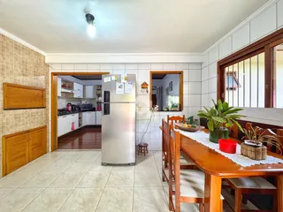 Ambiente interno de sala de jantar com cozinha visível.