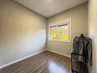 Ambiente interno com paredes neutras e piso de madeira clara.