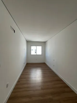 Foto de um corredor interno com piso de madeira e uma janela.