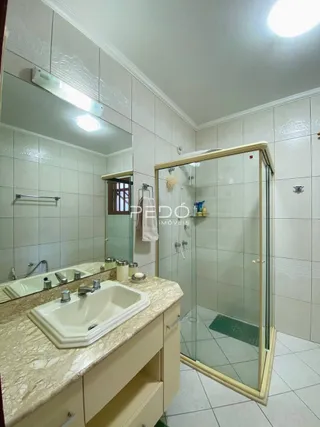 Foto de um banheiro com bancada e box de vidro em um imóvel.