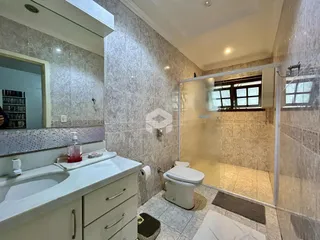 Foto de um banheiro com revestimento cerâmico e box de vidro.