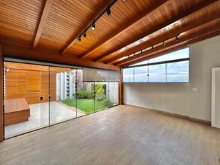 Uma sala de estar ampla com piso de madeira e portas de vidro que dão acesso ao jardim.