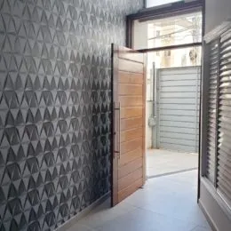 Parede com revestimento decorativo e porta de madeira em um ambiente interno.