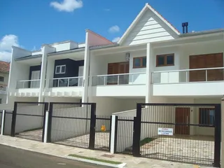 Fachada de uma casa residencial branca com muro e portão preto em Lajeado, Brasil.