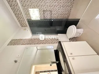 Banheiro com revestimento de azulejos e bancada branca.